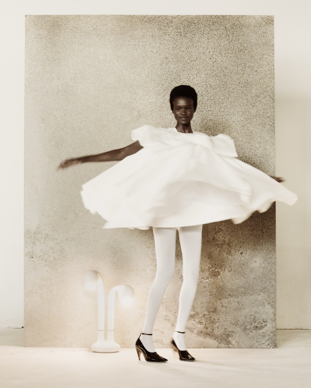 Vanguard fashion editorial with a model in a sculptural white dress beside an ENTLER lamp, photographed by @rexandjones